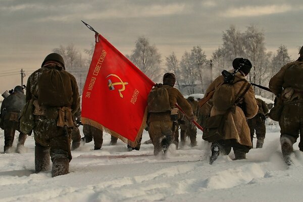 Soldados de asalto caminan sobre la nieve, llevando la bandera de la Unión Soviética