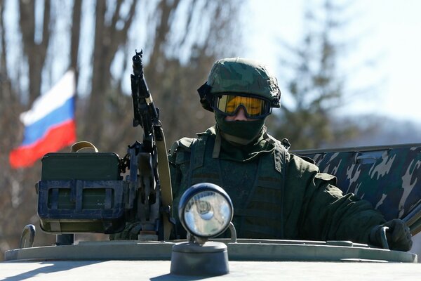 An armed soldier rides in a tank