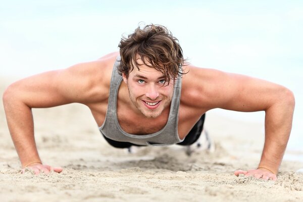 Les muscles d un homme pressant sur le sable