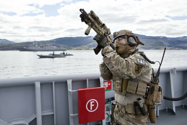 Soldado con armas en el fondo de las montañas