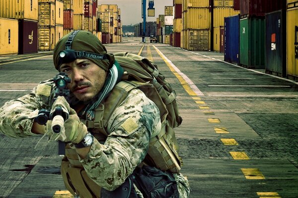 A man in military clothes takes aim at a machine gun