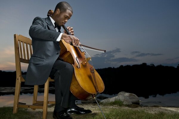 A musician is sitting on a chair against the sky