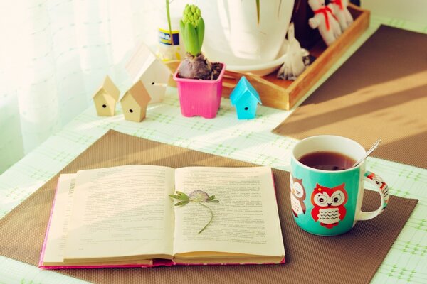 A cozy table with an open book and a cup of tea on it