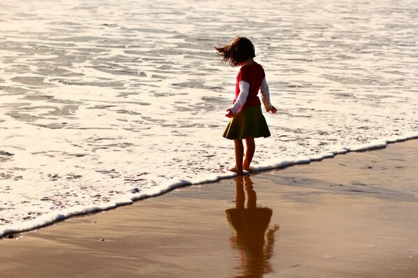 Fille mouille ses pieds dans l eau sur la plage