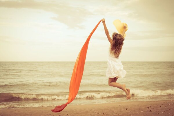 A girl with an orange scarf on the beach