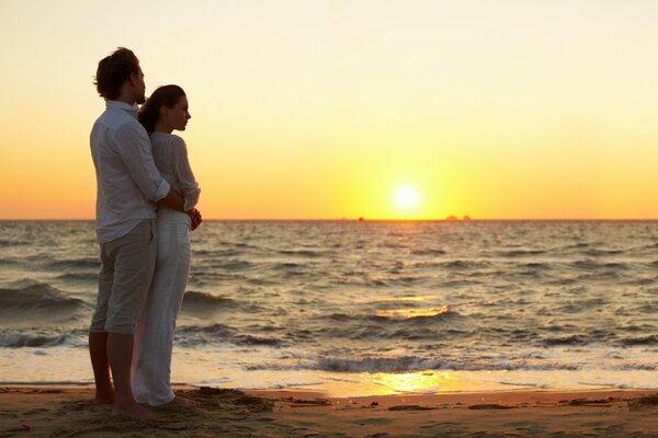 A couple admires the sunset on the seashore