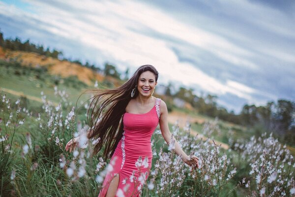 A joyful girl in a pink dress in the field