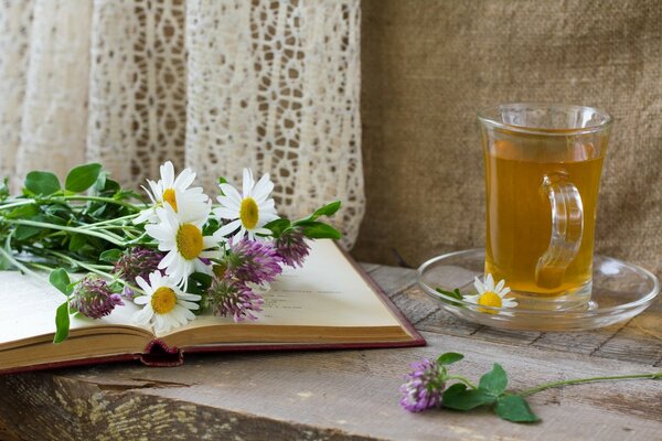 Tazza di tè sul tavolo con i fiori sul libro