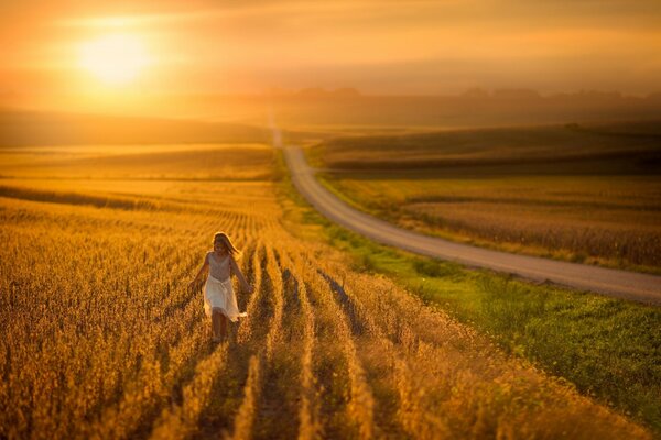 Una niña corre por el campo en los rayos del atardecer