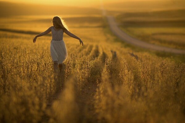 Fille court sur le champ dans les rayons du coucher du soleil