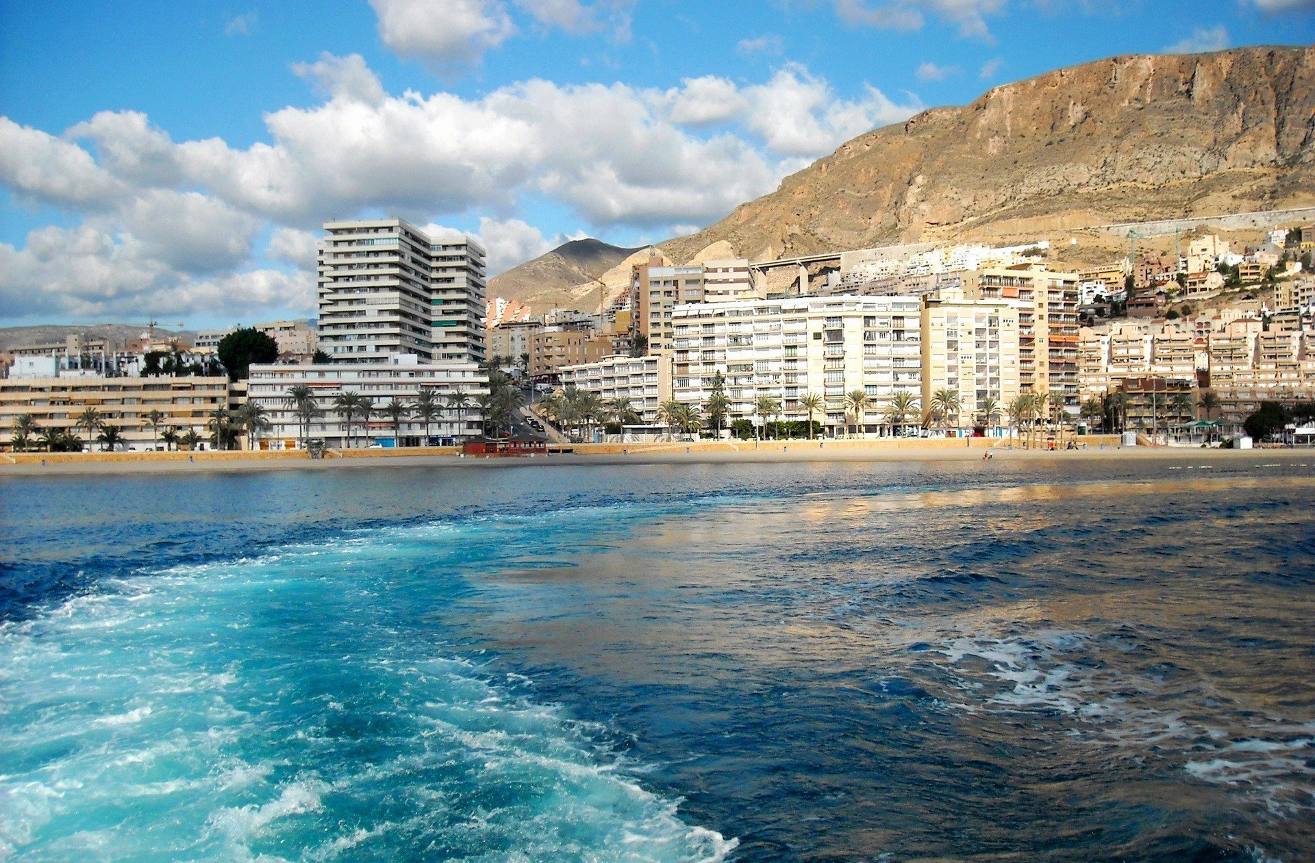 miasto kraj hiszpania andaluzja roquetas de mar góry budynki woda morze fale niebo chmury