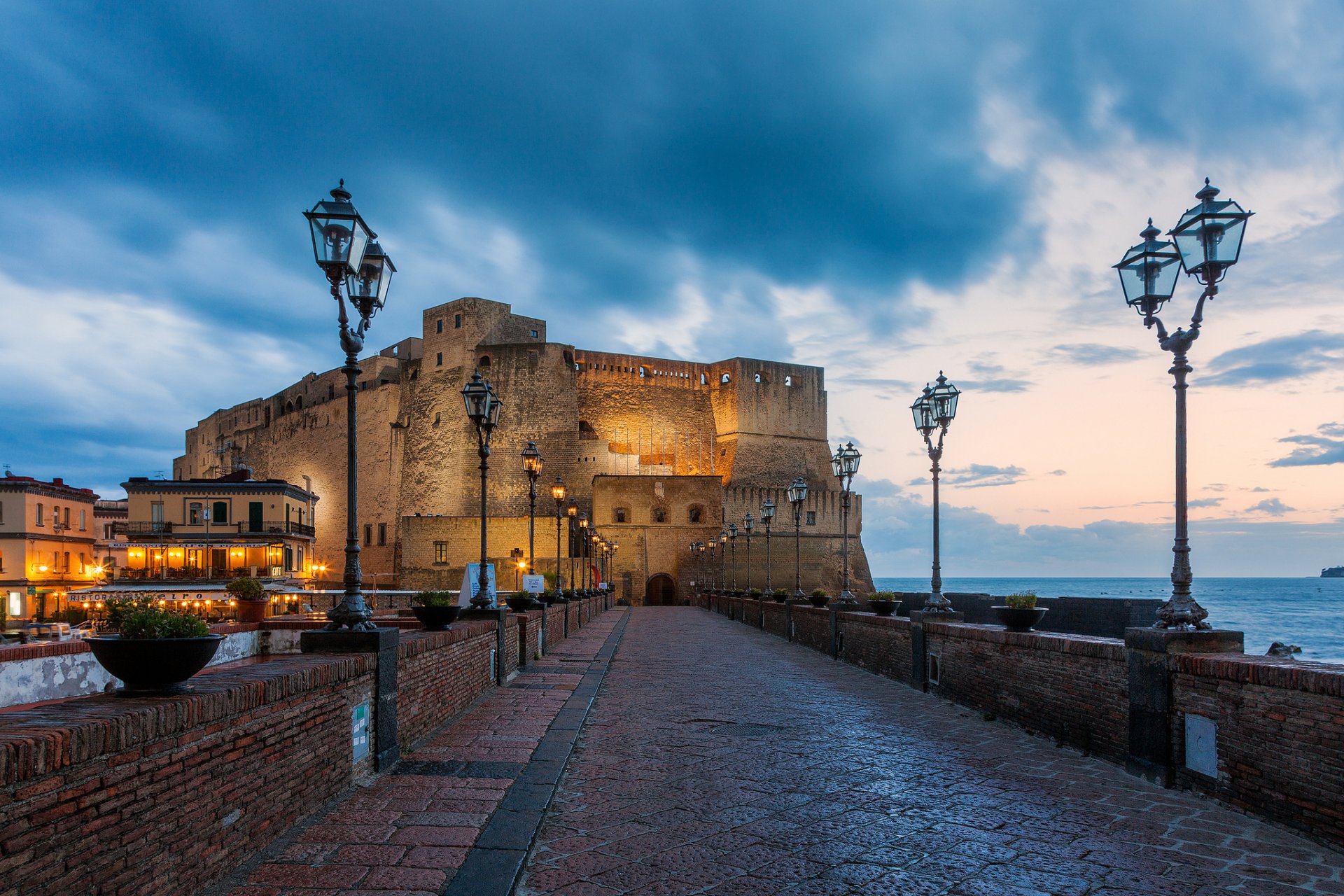 napoli italia włochy neapol castel del ovo castel del ovo zamek twierdza morze śródziemne tyrreńskie morze most latarnie wieczór miasto światła