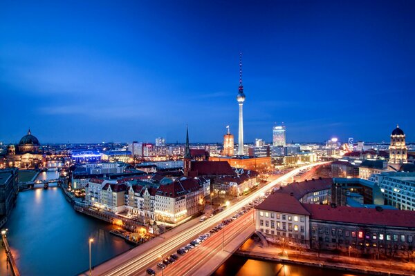 Panorama of Berlin at night with a bridge over the Thames and houses with a TV tower in the background