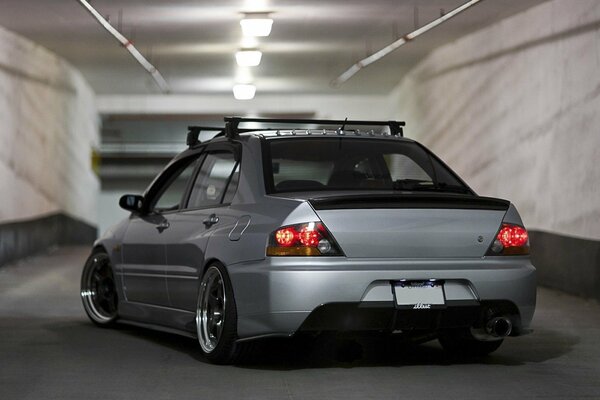 Mitsubishi Lancer the color of wet asphalt stands at the entrance to the underground parking lot