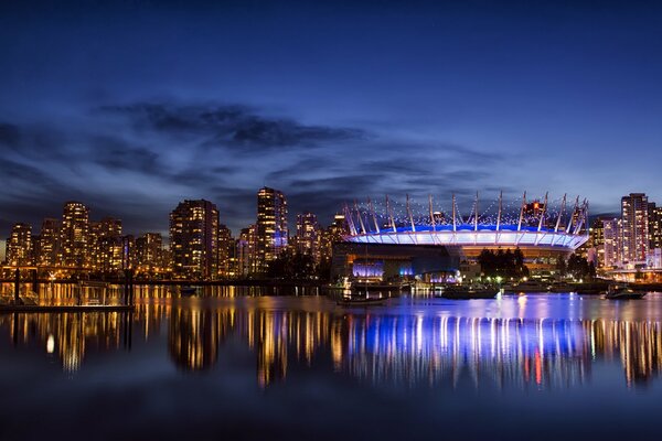 Vista de la ciudad nocturna. Reflejo de la ciudad en el agua