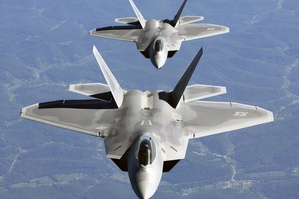 A pair of Raptor f 22 planes fly through the sky