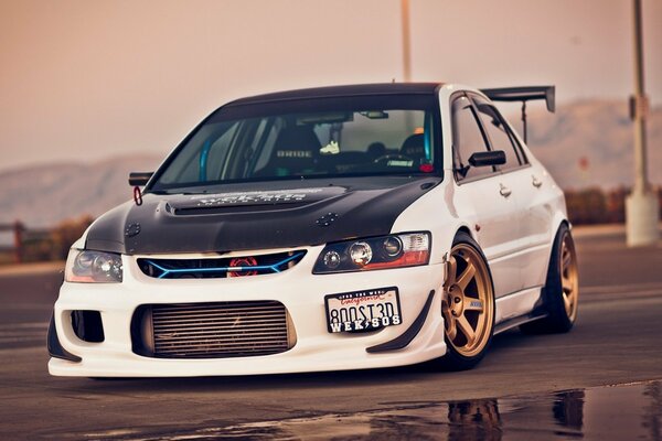 White with black hood Mitsubishi Lancer sports car on the background of mountains