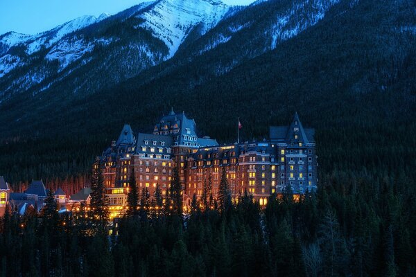 Edificio nocturno del parque nacional Canadiense en medio de montañas cubiertas de nieve