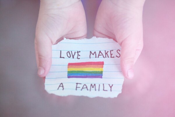 Drawing of a rainbow on a piece of paper with an inscription in the hands of a child