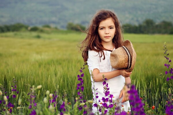 Una niña de flores moradas sostiene un sombrero