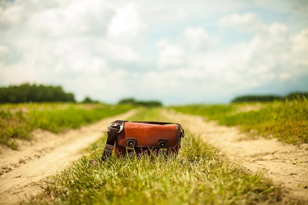 The bag lies on the road in the middle of a peaceful field