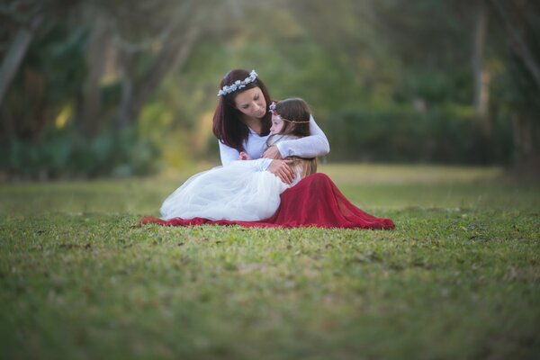 Mother and child hug sitting on the field