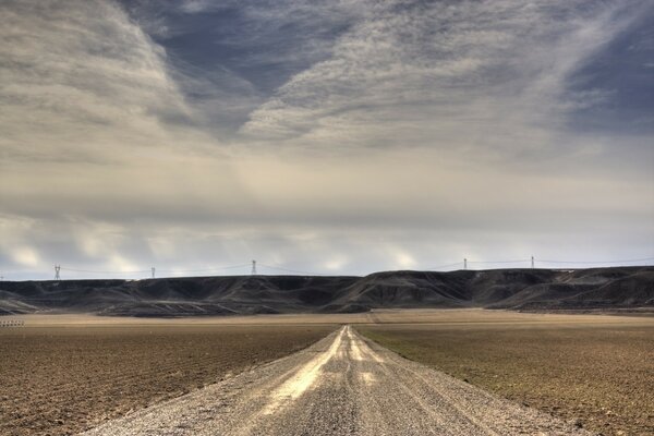 A long road in the desert, clouds and a road