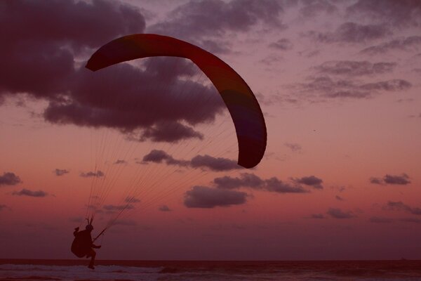 Parapente en el fondo del cielo rosado de la puesta del sol