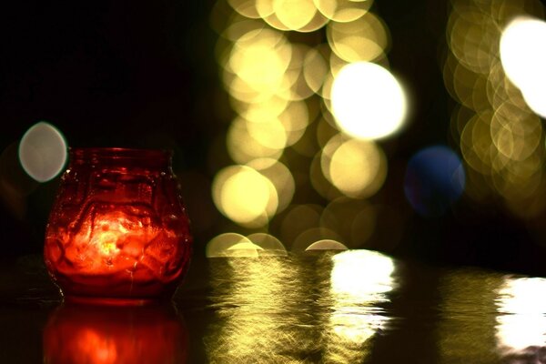 A candle is burning in a red jar