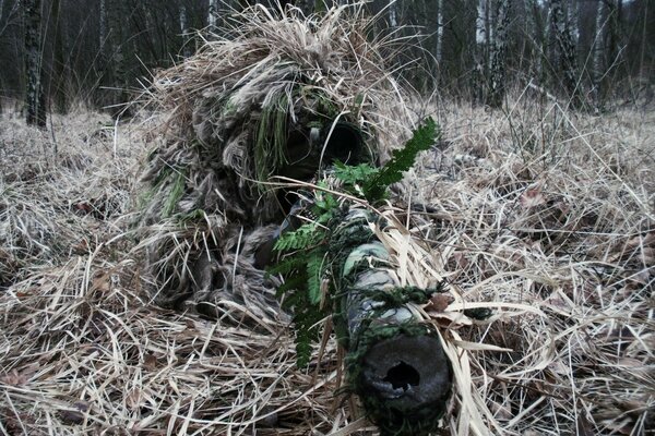 Scharfschütze mit Gewehr in Tarnung getarnt