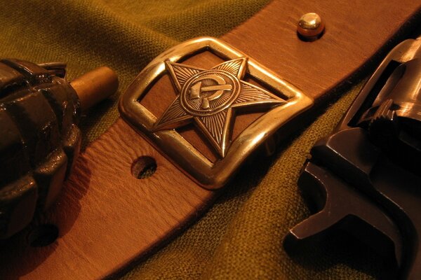 A soldier s belt with a metal plaque of the USSR , a grenade , a pistol trigger