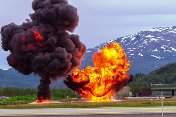 Explosion in der Nähe der Straße vor dem Hintergrund eines Berges