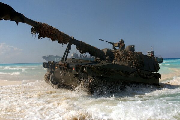 Tank vor dem Hintergrund des blauen Meeres und des gelben Sandes