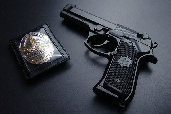 Pistola y insignia de oficial de policía sobre fondo negro