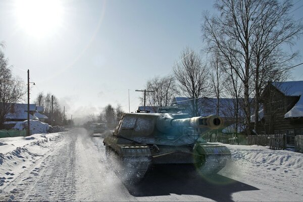 In inverno, un carro armato attraversa il villaggio lungo la strada