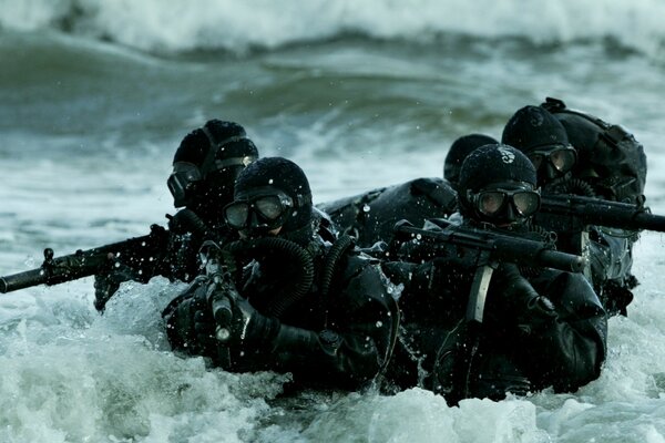 Militari con armi in mare tra le onde