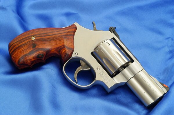 Revolver with a wooden handle on blue satin