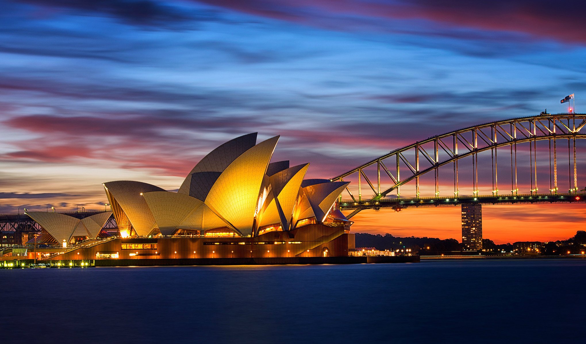 australia sydney opera house ponte sera luci illuminazione arancione tramonto cielo nuvole baia mare