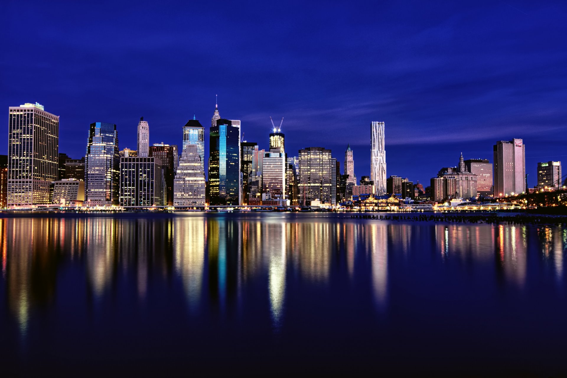 usa new york metropolis buildings skyscrapers night illumination lights blue sky river reflection