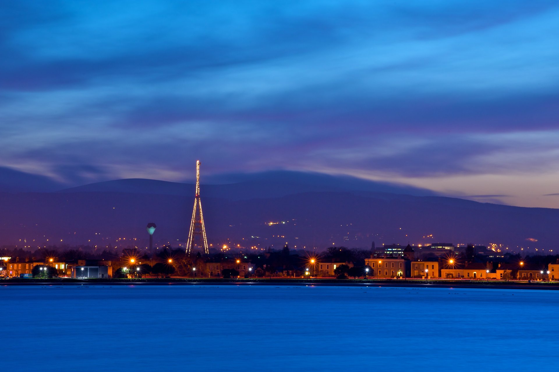 ireland dublin capital capital evening twilight sky blue clouds mountains houses lights lights lanterns embankment river