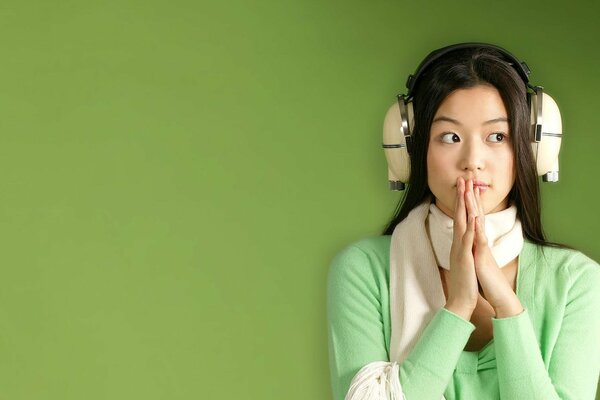 Chica morena en los auriculares sobre un fondo verde