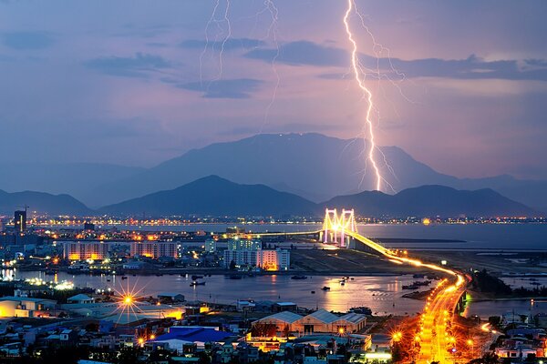 Evening city on the background of mountains and lightning