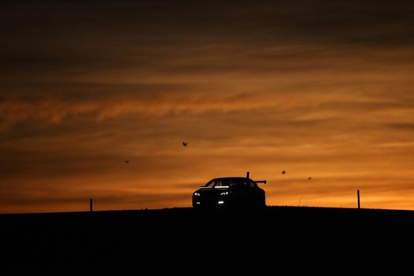 Silueta del coche en el fondo de la puesta de sol