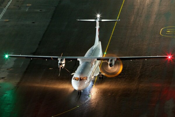 A plane with burning lights at the airfield at night