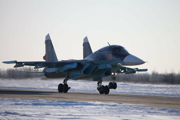 A fighter jet on the runway against the background of snow-covered fields