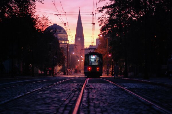 Tranvía de la ciudad en la puesta de sol rosa