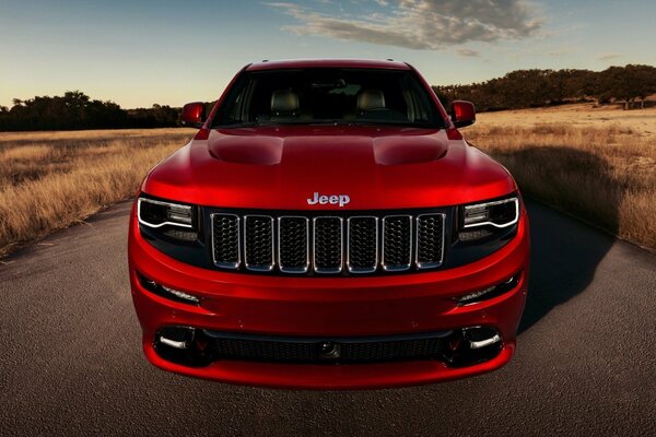 Czerwony JEEP grand cherokee na tle pola