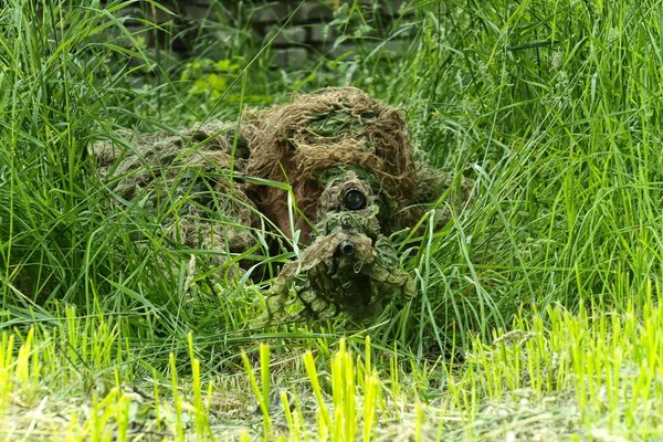 Der Scharfschütze sitzt in Tarnung in einem Hinterhalt