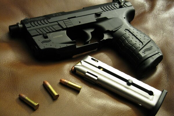 Fotografía de una pistola Walter con cartuchos sobre un fondo de cuero marrón