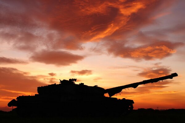 Silhouette of a large tank against the background of a bright sunset